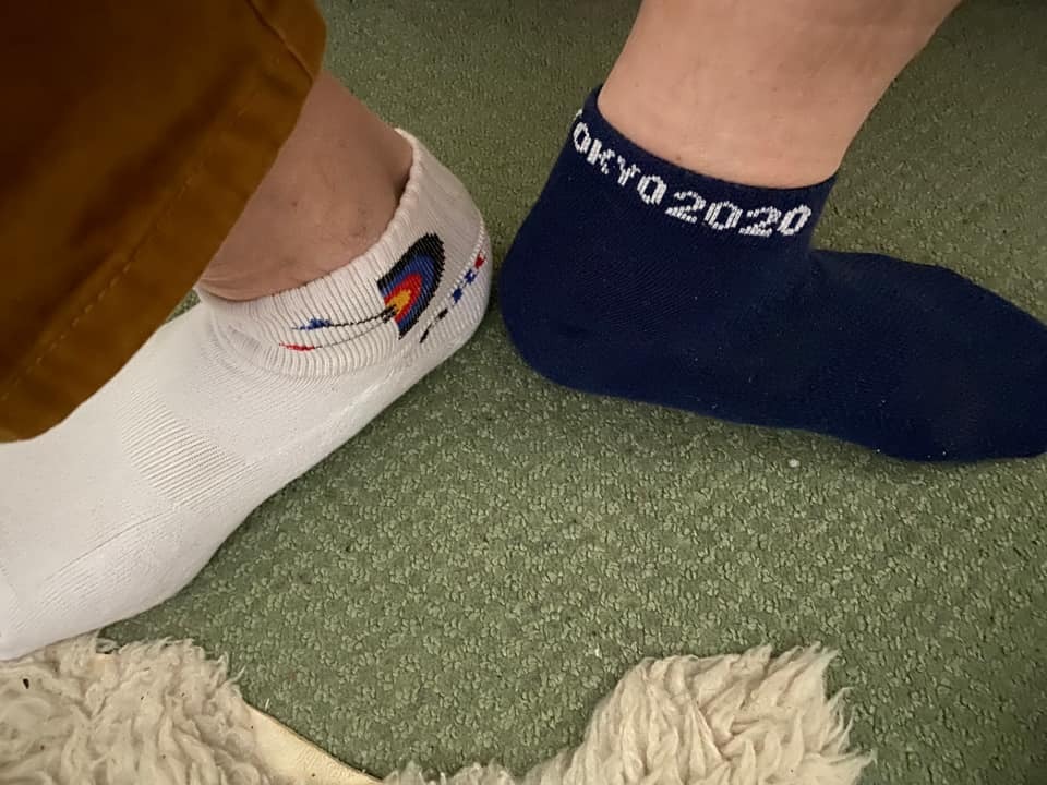 Feet wearing odd socks that feature archery targets and the words Tokyo 2020